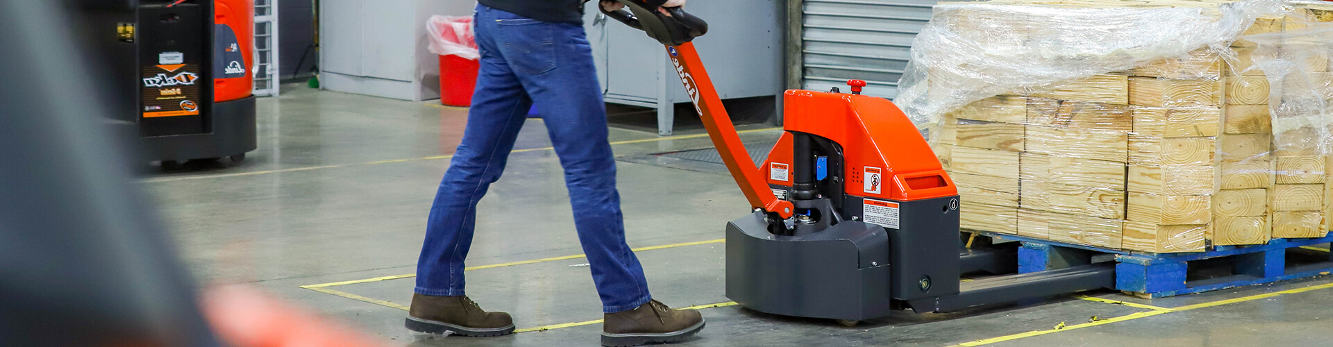 Person working with an industrial hand pallet truck loading a wooden pallet